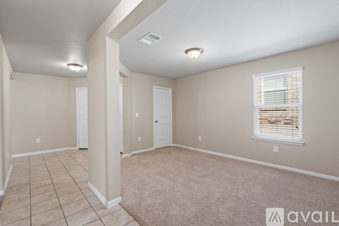 A spacious room with beige walls and a window with blinds.