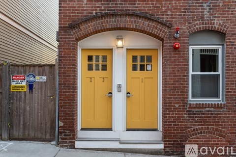 A yellow door is on the right side of a brick building.