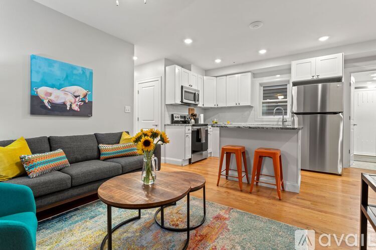 A living room with a grey couch and a coffee table with a vase of flowers on it.