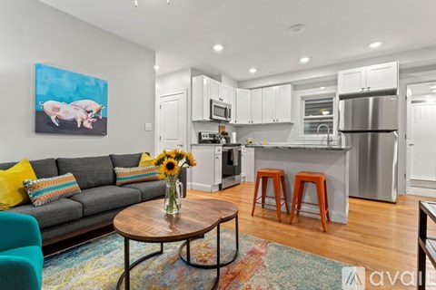 A living room with a grey couch and a coffee table with a vase of flowers on it.