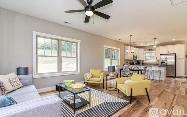 A living room with a grey couch, yellow chairs, and a ceiling fan.