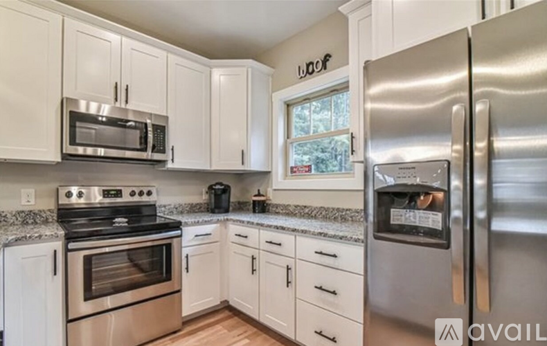 A kitchen with white cabinets and a stainless steel refrigerator.