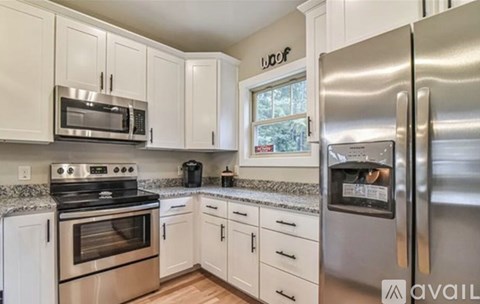 A kitchen with white cabinets and a stainless steel refrigerator.