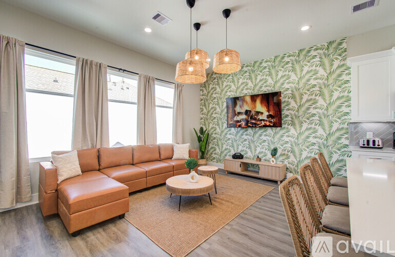A living room with a brown leather couch and a white kitchen area.