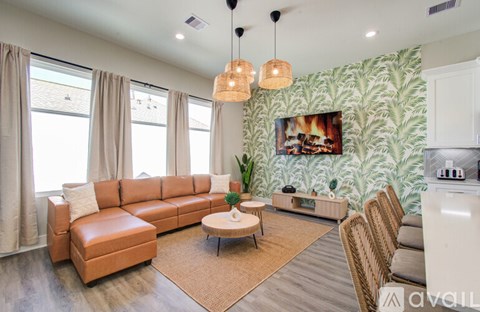 A living room with a brown leather couch and a white kitchen area.