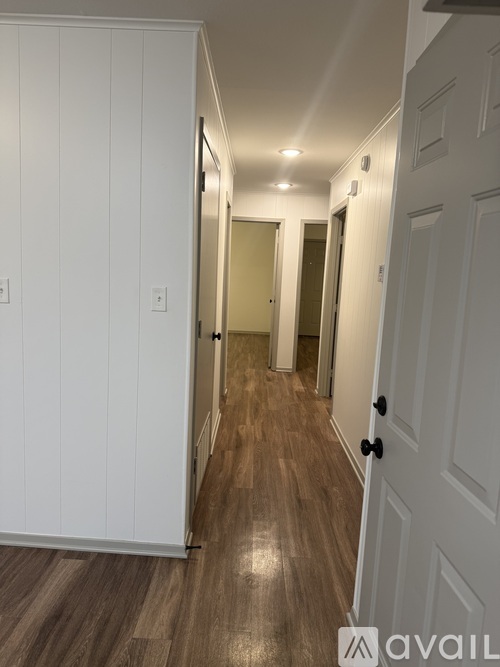 A hallway with white walls and wood flooring.