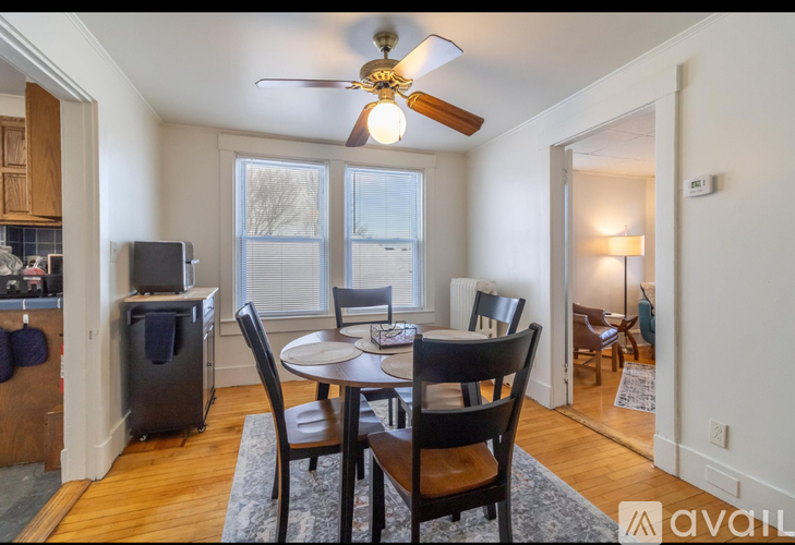 A dining room with a table set for four and a ceiling fan.