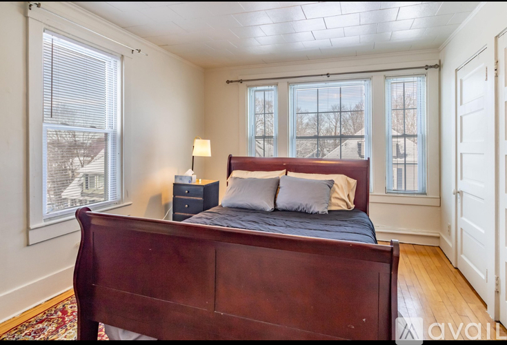 A bedroom with a large bed and a window with blinds.