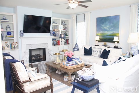 A living room with a fireplace, a chair, a sofa, and a painting on the wall.