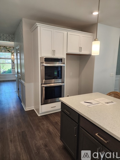A kitchen with white cabinets and a wooden floor.