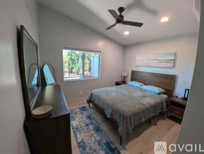 A bedroom with a bed, dresser, mirror, and a ceiling fan.