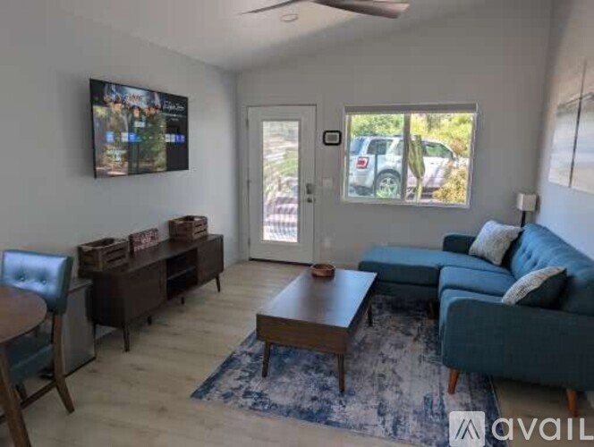 A living room with a blue couch and a television mounted on the wall.