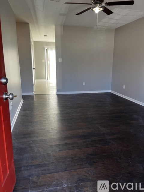 A room with a red door and wooden flooring.