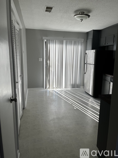 A black and white photo of a kitchen with a refrigerator, cabinets, and a door.