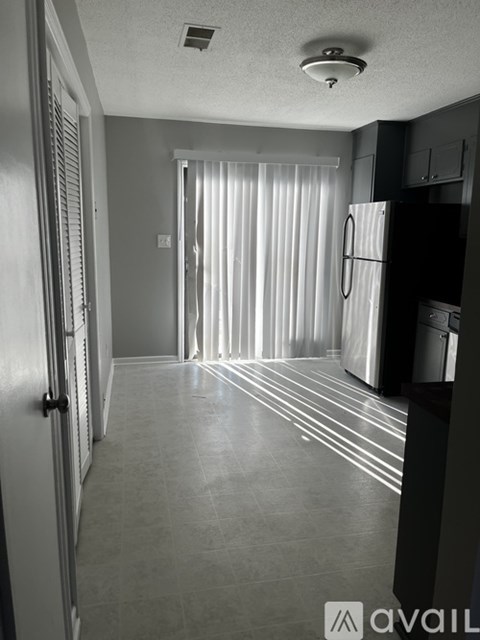 A black and white photo of a kitchen with a refrigerator, cabinets, and a door.