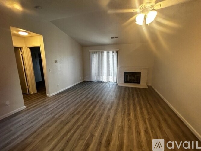 A spacious room with wooden flooring and a fireplace.