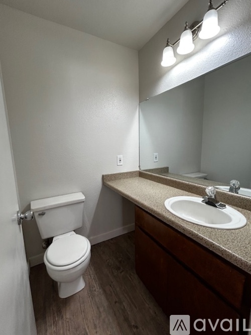 A bathroom with a toilet, sink, and mirror.
