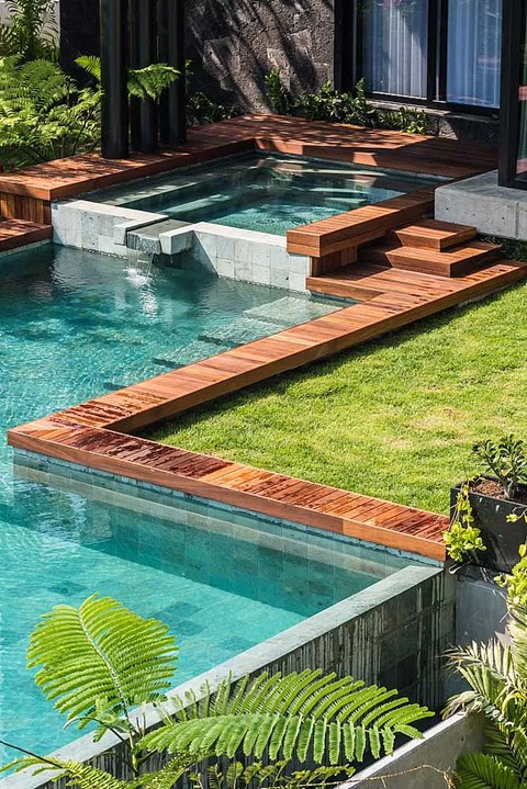 A small pool with a wooden deck and steps.