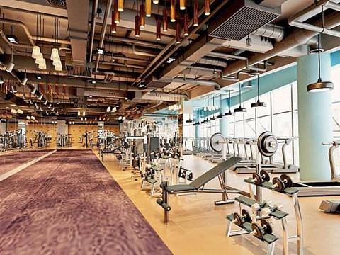 A gym with a variety of equipment including treadmills, weights, and exercise machines.