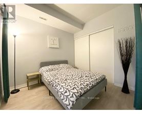 A bedroom with a bed, nightstand, and lamp.