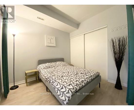 A bedroom with a bed, nightstand, and lamp.