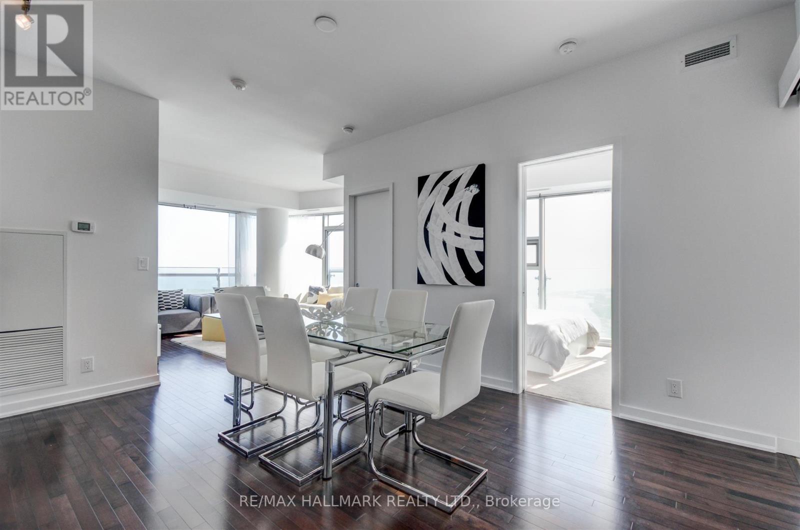A dining room with a glass table and white chairs.