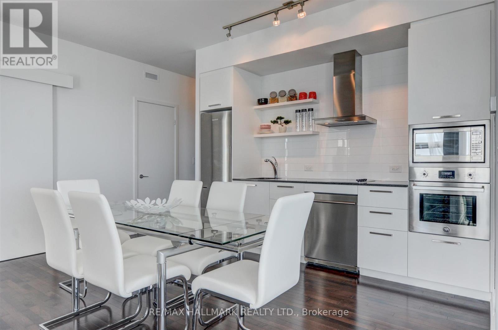 A modern kitchen with white chairs and stainless steel appliances.