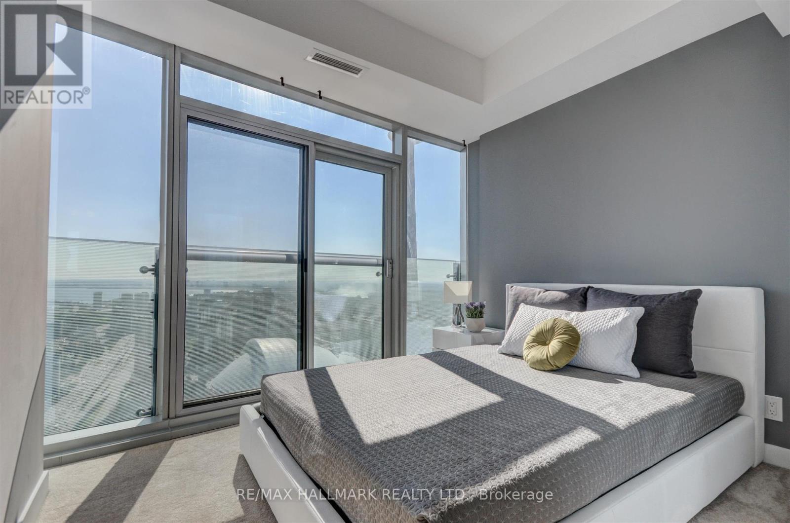 A bedroom with a large bed and a view of the city through the windows.