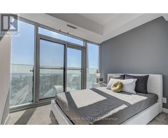 A bedroom with a large bed and a view of the city through the windows.