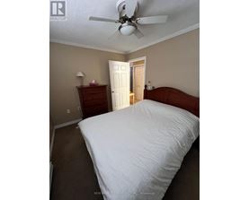 A bedroom with a large bed and a ceiling fan.