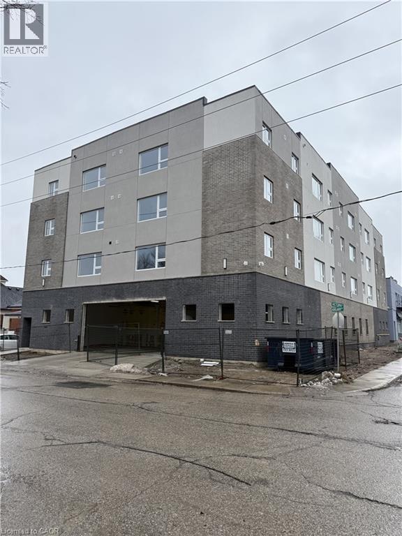 A large, multi-story building with a grey facade and a black fence in front.