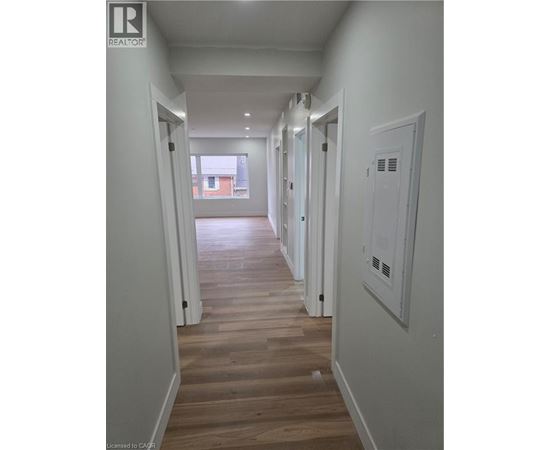 A long hallway with wood floors and white walls.