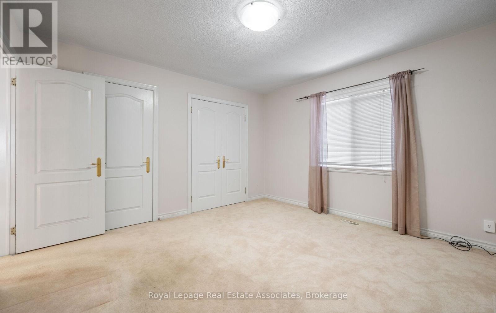A white bedroom with a window and curtains.