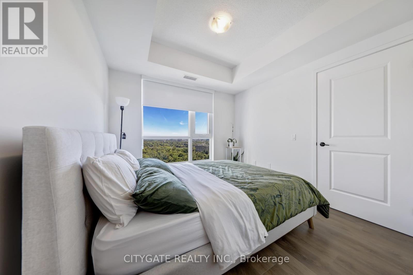 A bedroom with a large bed and a view of the outdoors through the window.