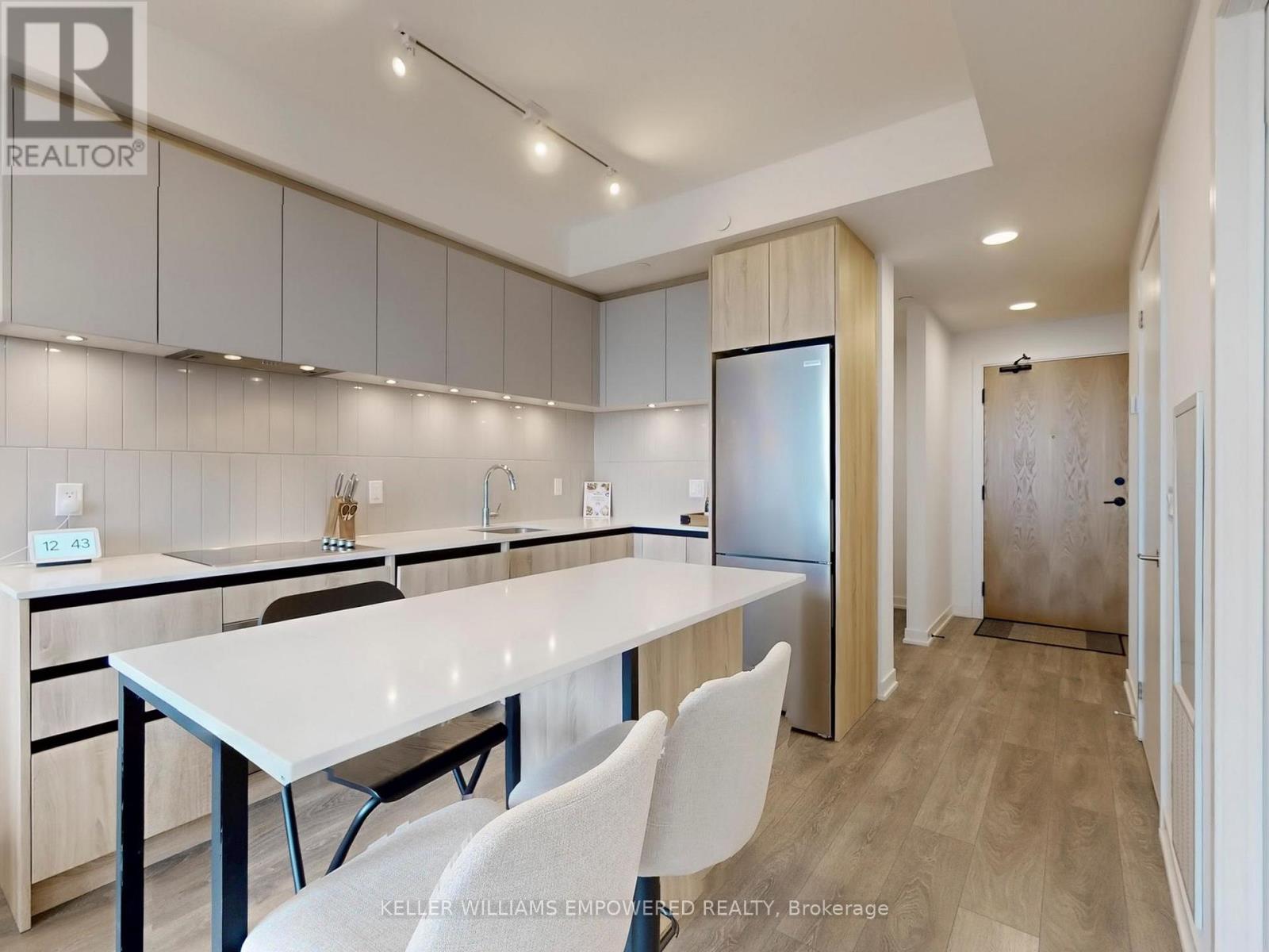 A modern kitchen with a long white table and chairs.