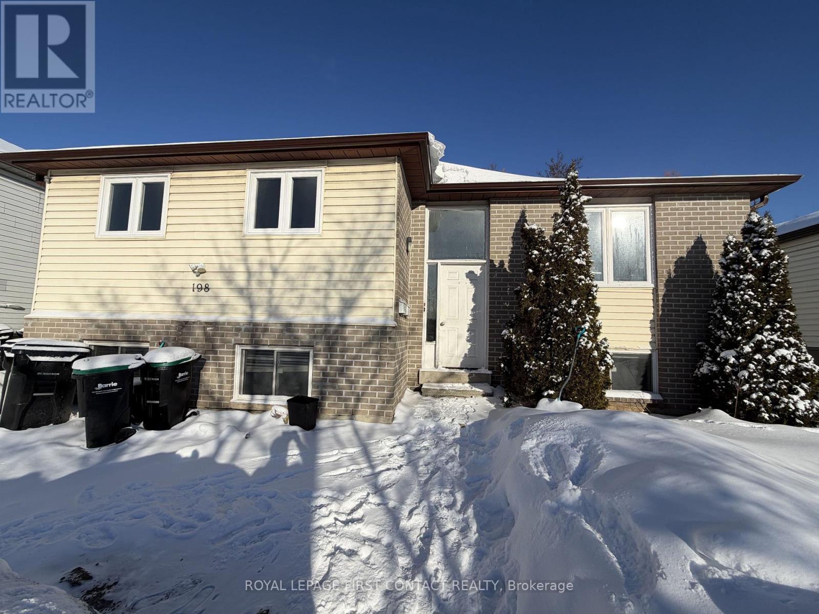 A house with snow on the ground and trees in front.