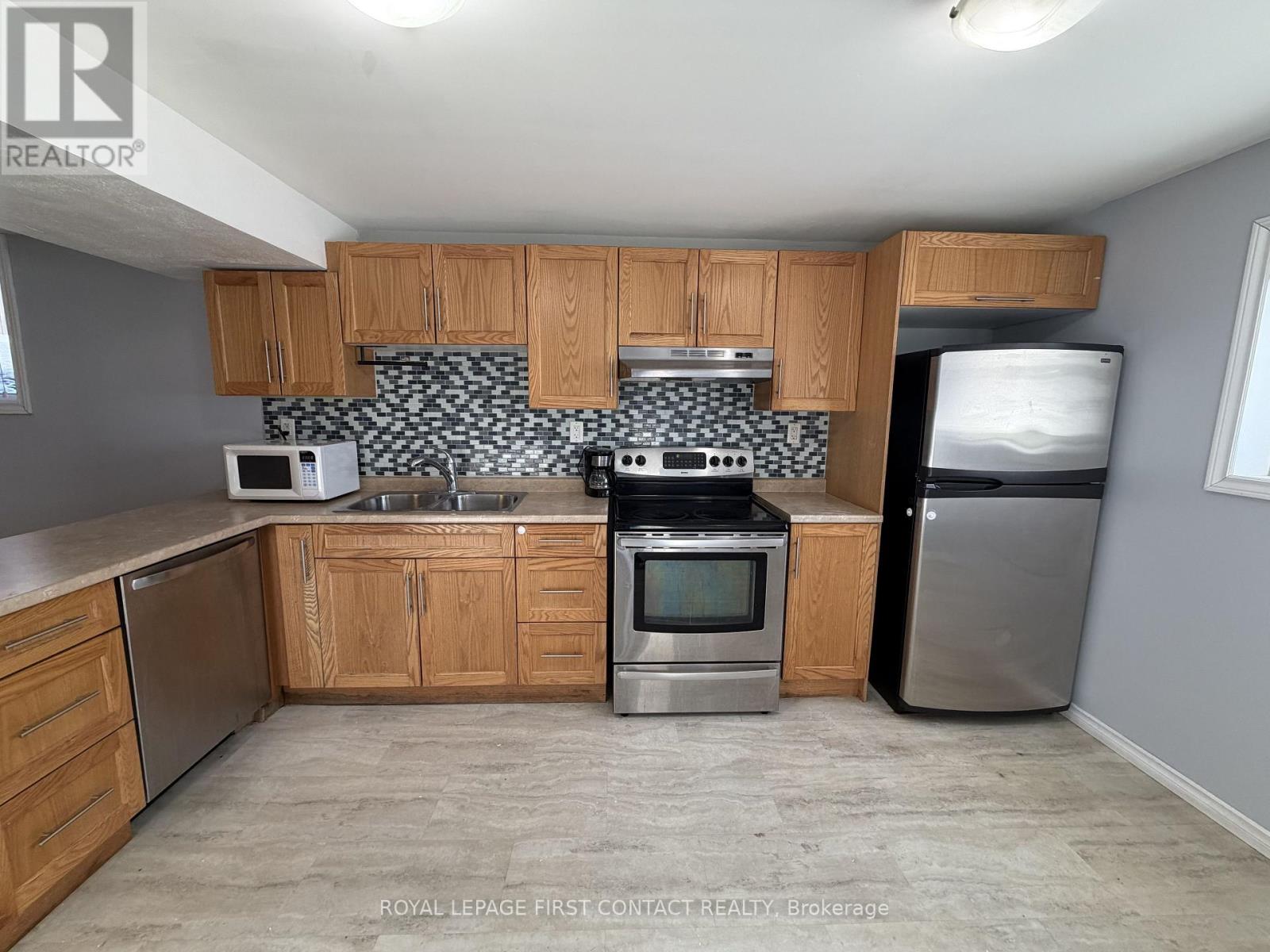 A kitchen with wooden cabinets and a black and white backsplash.