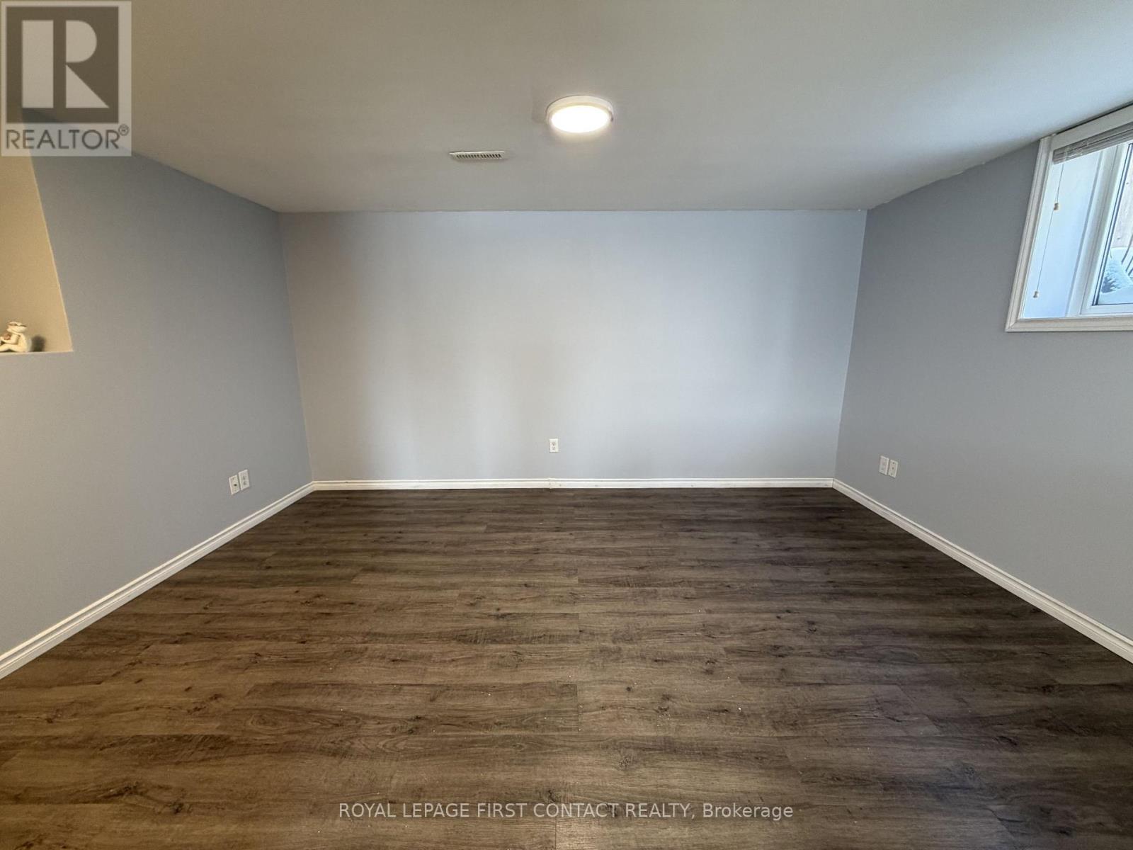 A spacious room with wooden flooring and white walls.