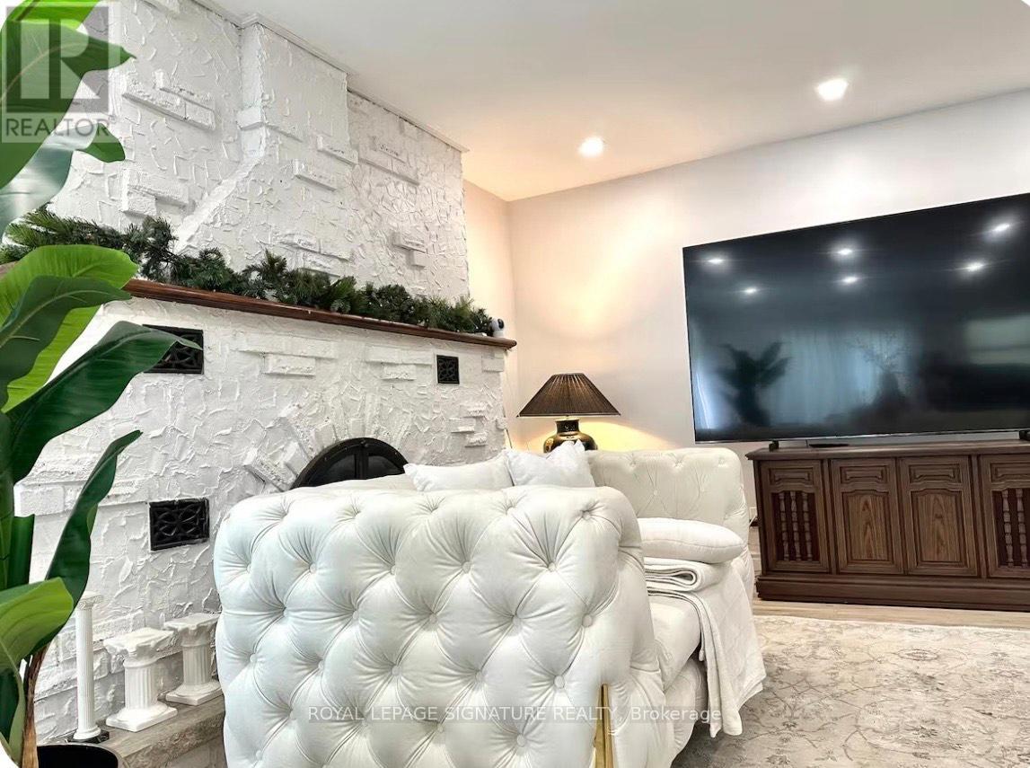 A white tufted chair sits in front of a fireplace in a room with a large screen.