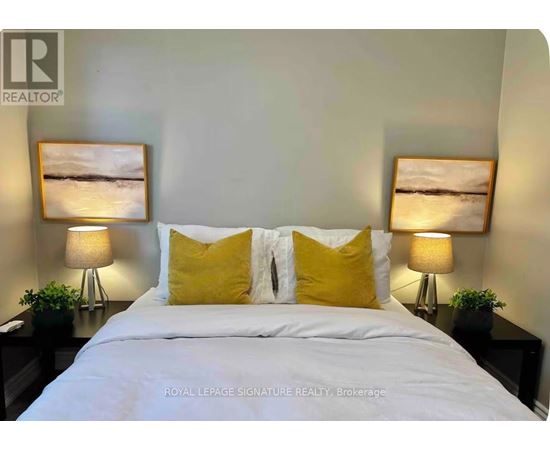 A bedroom with a white bed and two yellow pillows.