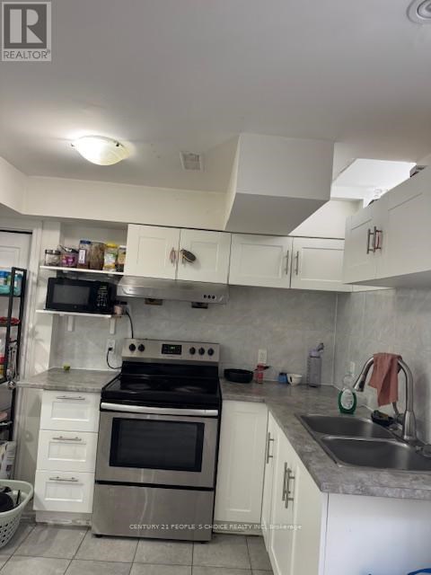 A kitchen with white cabinets and a stove top oven.