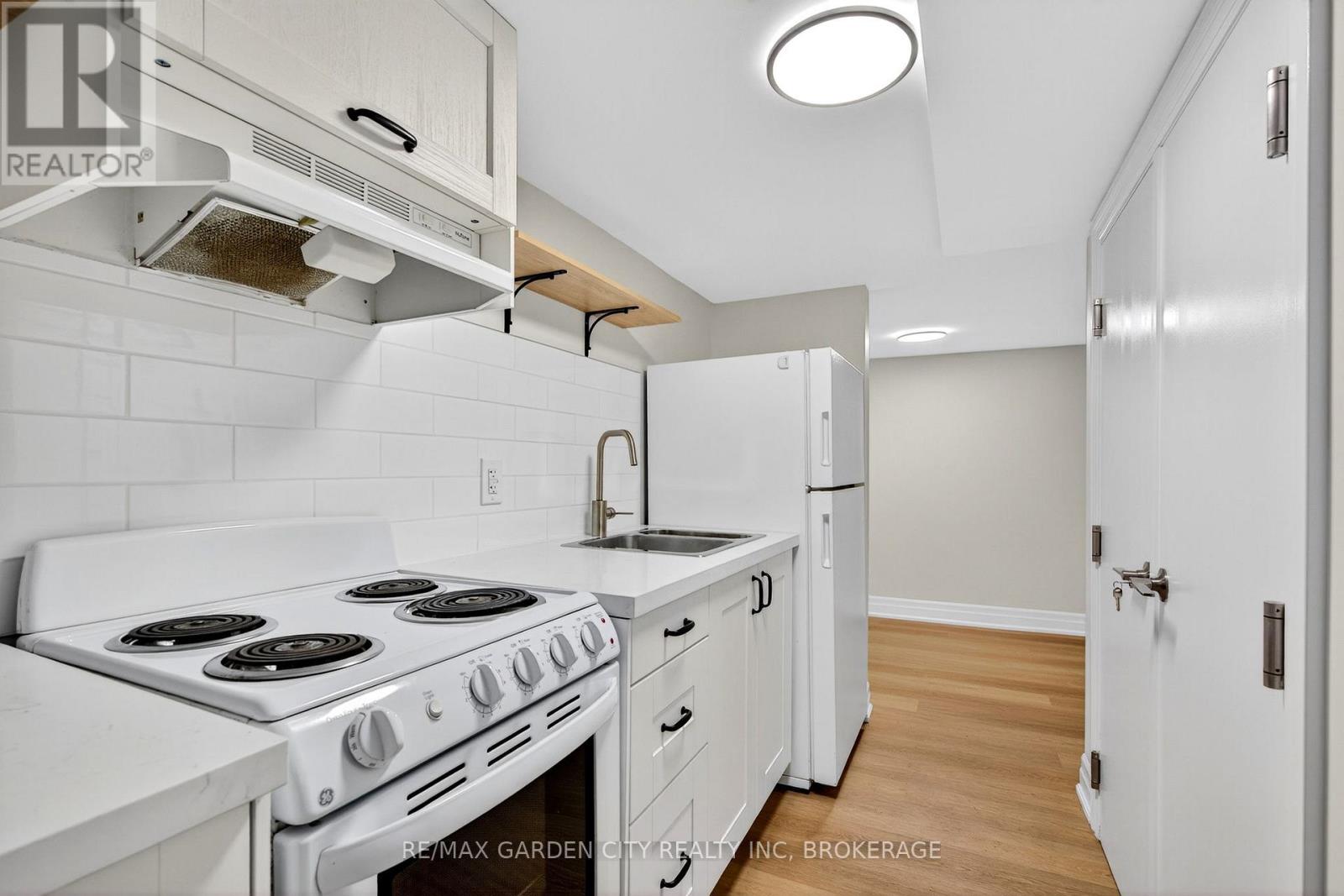 A white kitchen with a stove top oven and a refrigerator.
