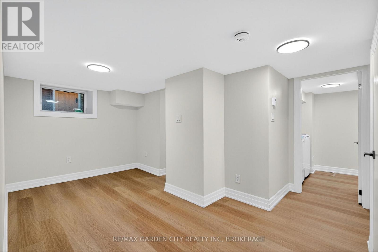 A spacious room with wooden flooring and white walls.
