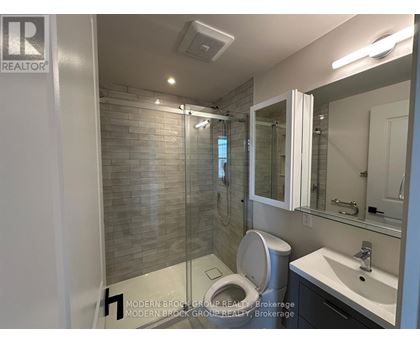 A bathroom with a toilet, sink, and glass shower stall.
