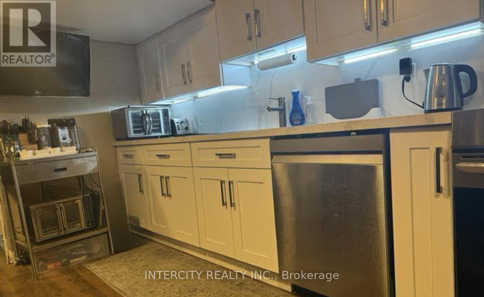 A kitchen with white cabinets and a stainless steel refrigerator.