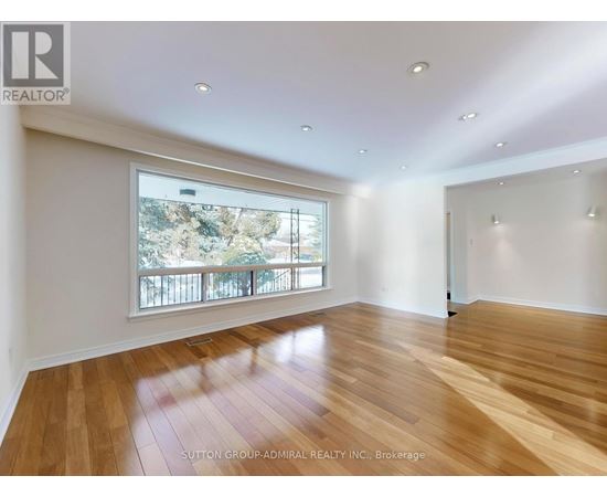 A spacious room with wooden flooring and a large window overlooking a balcony.