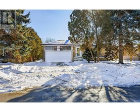 A house with a white garage door is surrounded by snow.