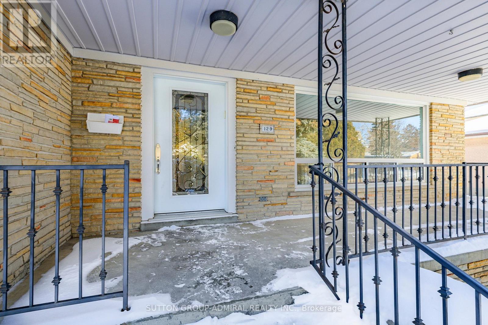 A house entrance with a white door and a black metal railing.