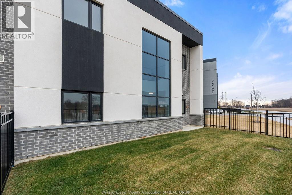 A modern building with a black fence and a grassy area in front.