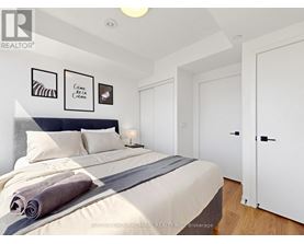 A bedroom with a large bed and a city view through the window.